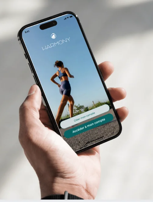 Écran de connexion de l'application mobile Harmony sur un iPhone tenu en main